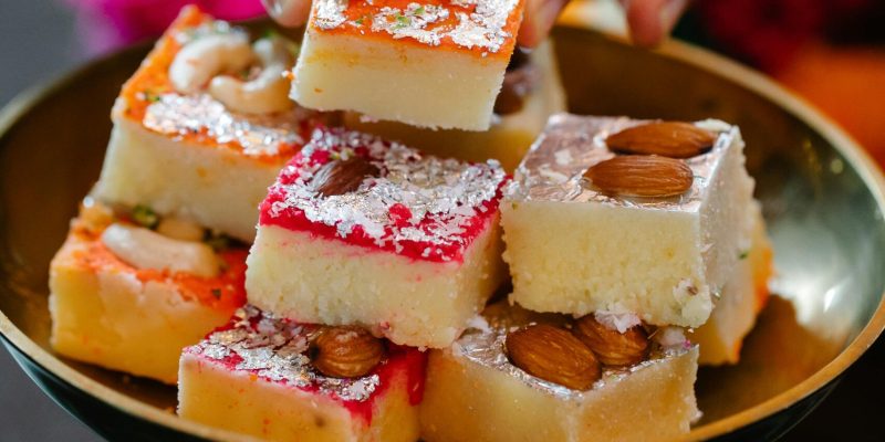 Close-up of assorted Indian sweets on a metallic tray, perfect for festive celebrations.